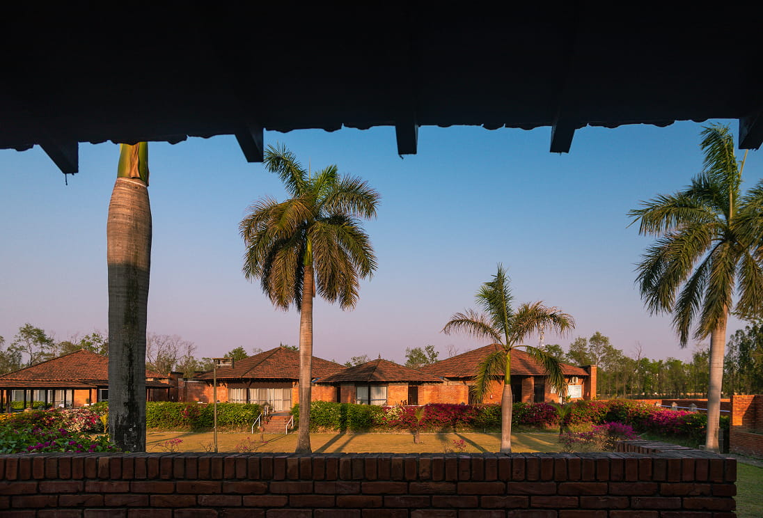 Palm trees and red-roofed buildings of Hokke Hotel at sunrise, seen from a veranda