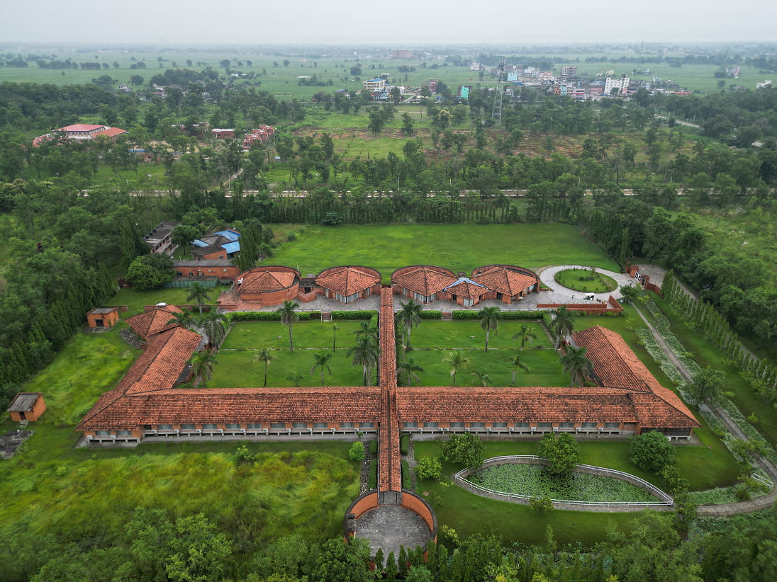 Aerial view of Hokke Hotel's red-roofed courtyards among green fields in Lumbini