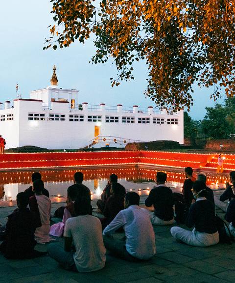 Pilgrims gathered under a tree facing the Maya Devi Temple in Lumbini