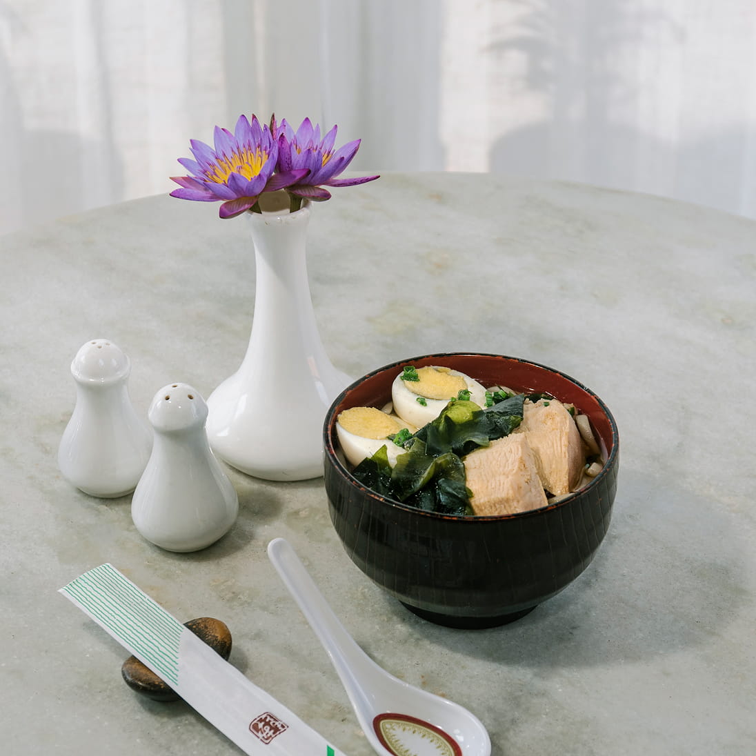 Bowl of Japanese soup beside a lotus flower vase at Hokke's restaurant