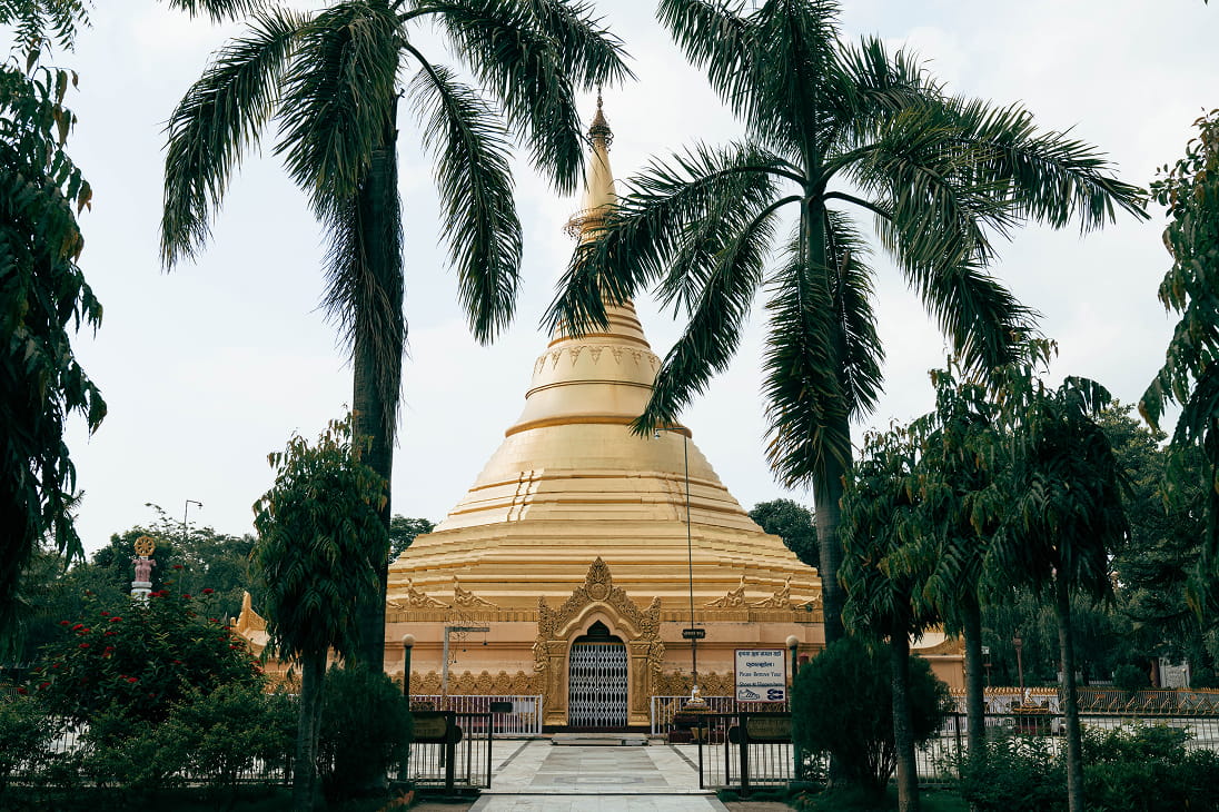 Golden Burmese pagoda framed by palm trees in Lumbini