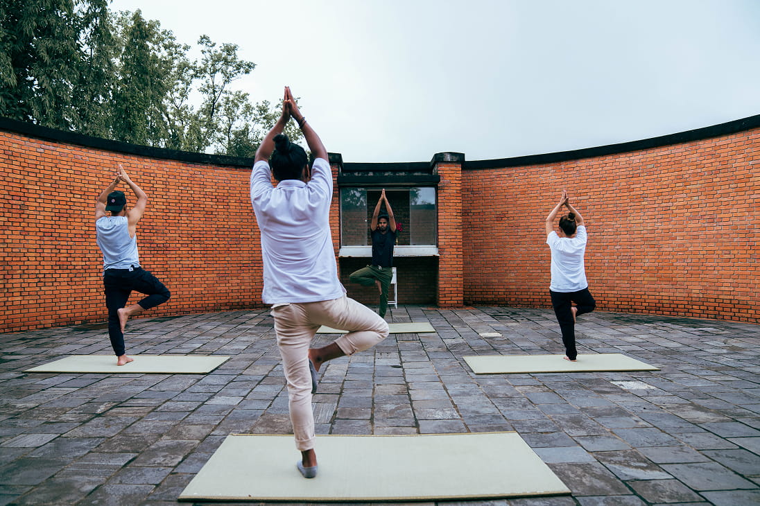 Guests practising tree pose in Hokke Hotel's brick-walled yoga court