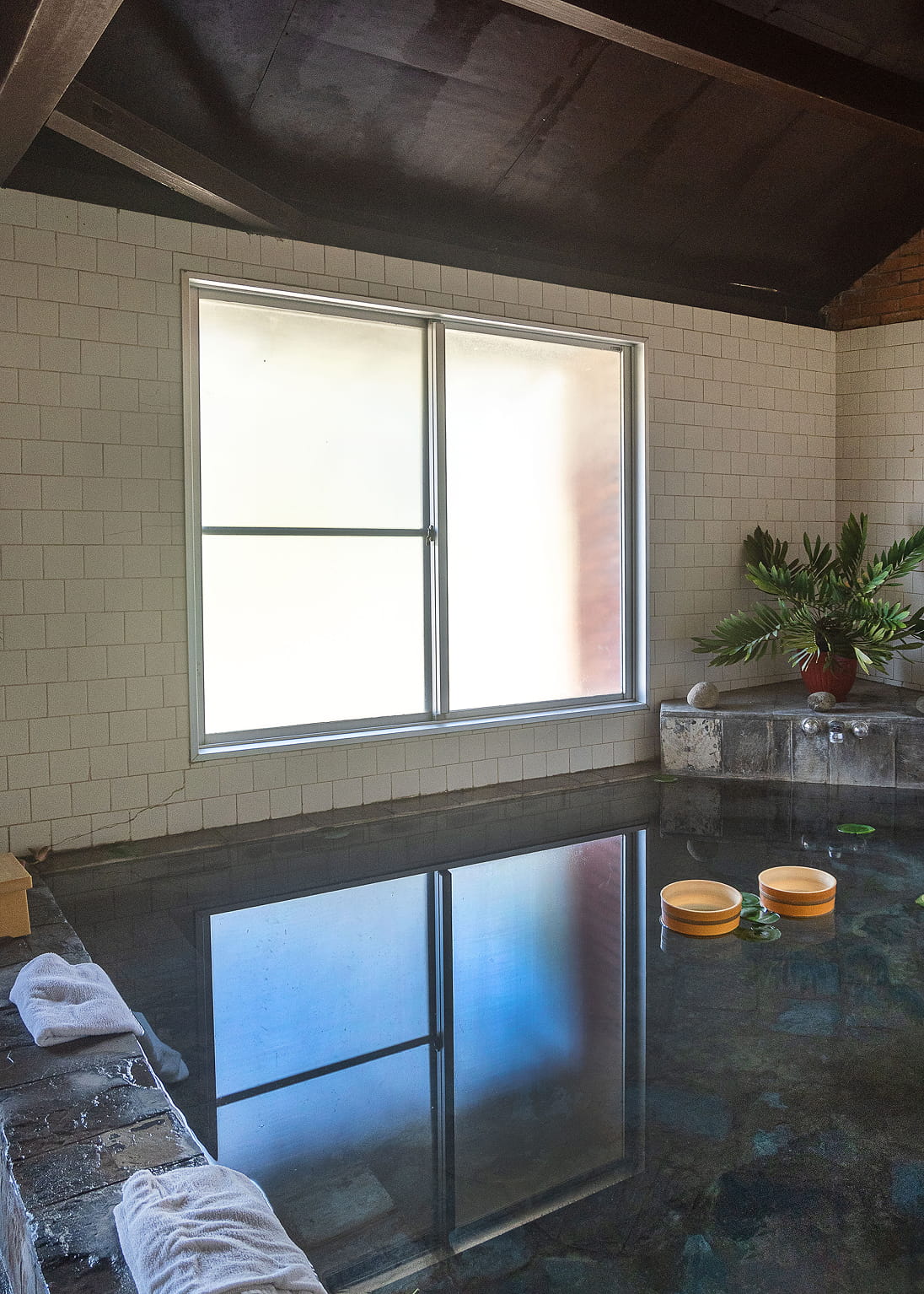 Indoor Japanese bath with still water and wooden pails at Hokke Hotel