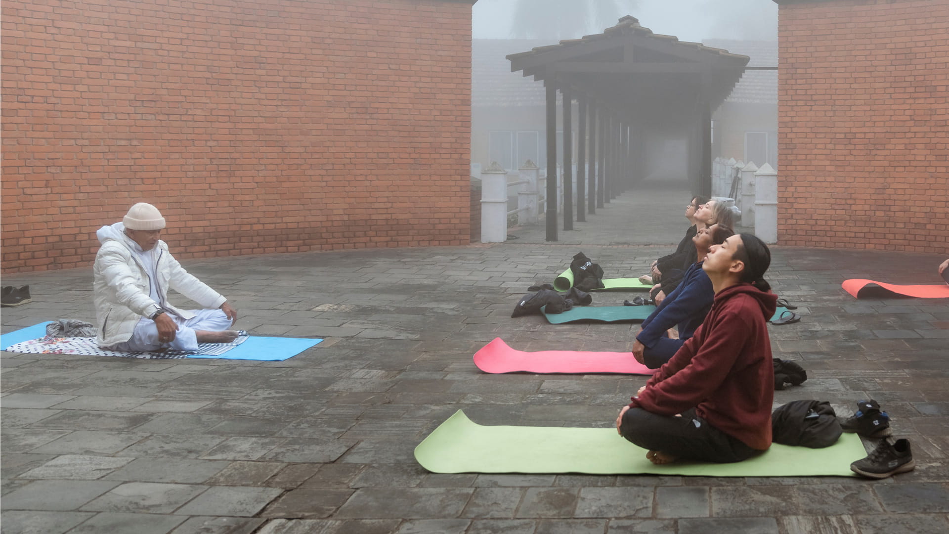 Morning meditation and yoga on mats in a misty courtyard at Hokke Hotel